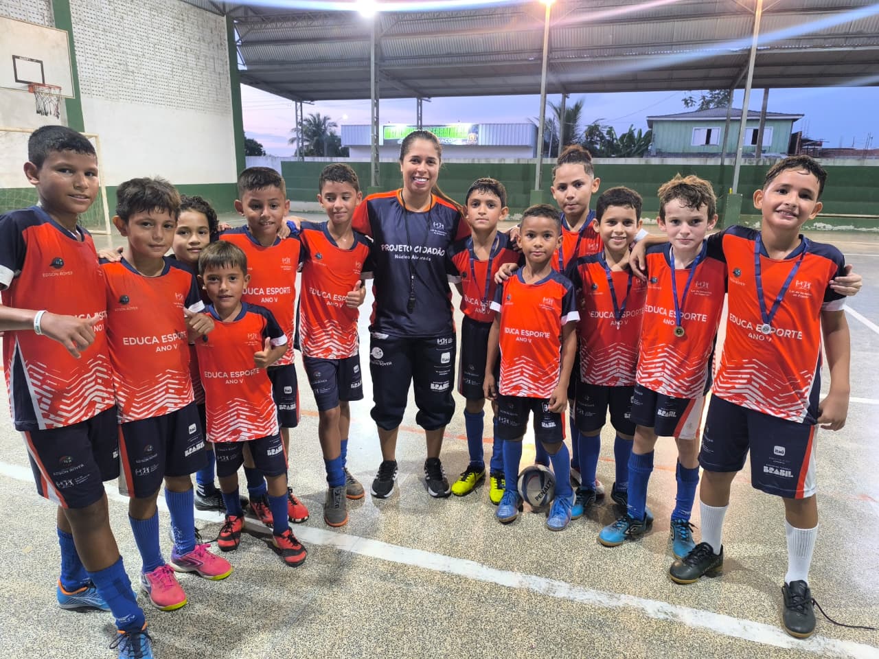 Foto da professora prisciele junto de seus alunos em quadra